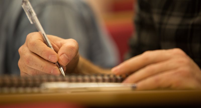 Close-up of person writing in a notebook.