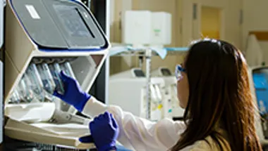 Woman introducing test tubes in machine