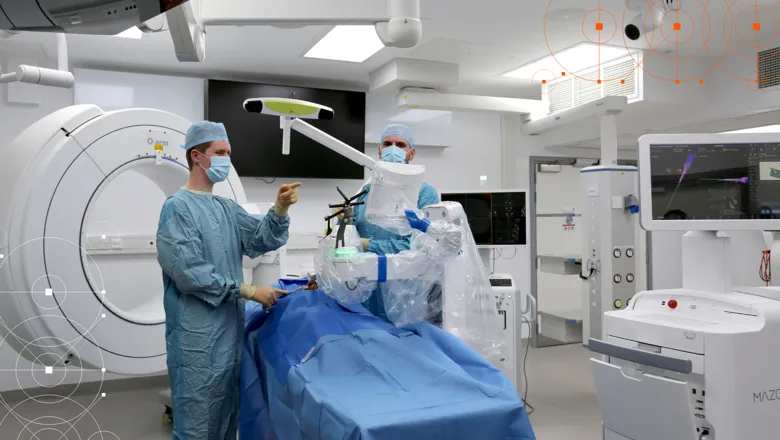 Two surgeons in the operating theatre around an operating bed and looking at a screen