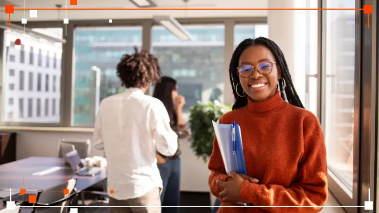 Young black woman standing in classroom posing with pad and pen