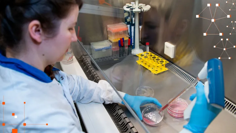 woman in lab coat using pipette and petri dish