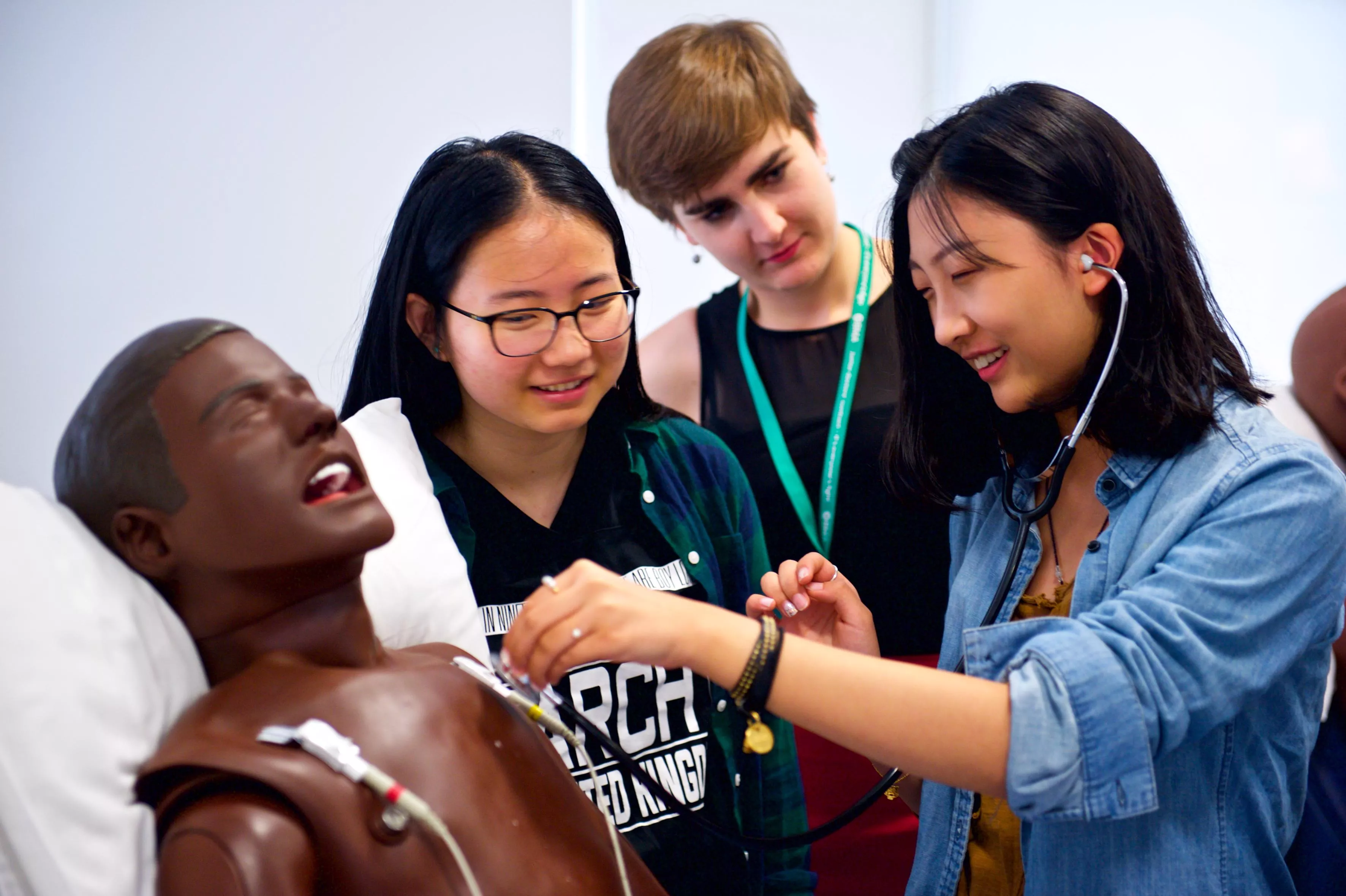 Medical students listening for a heartbeat on a training manikin