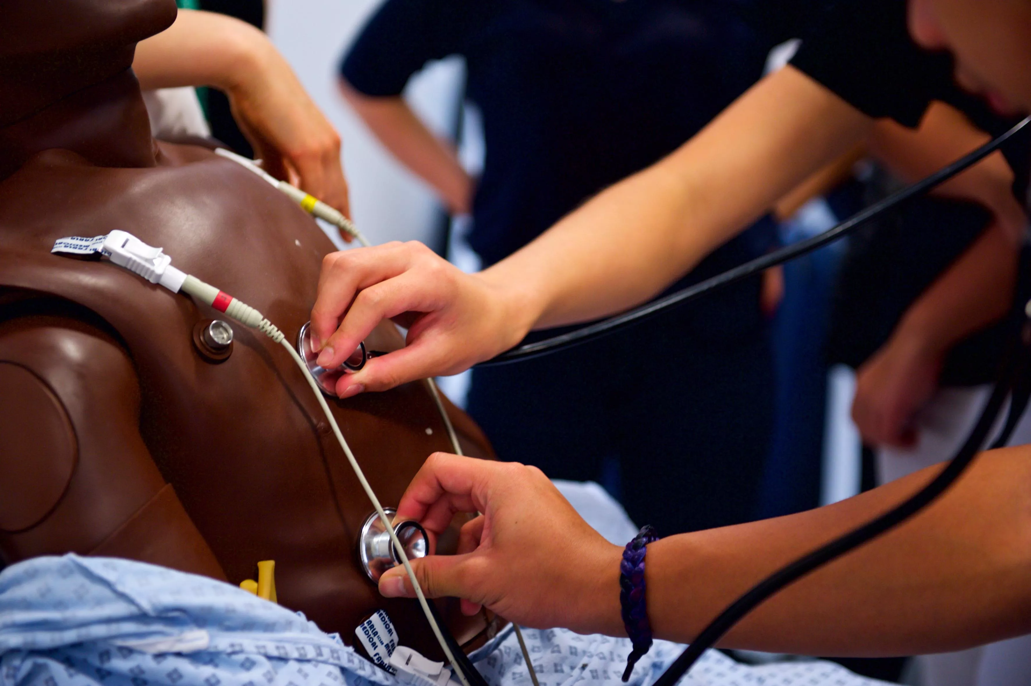 medical students listening for a heartbeat on a training manikin