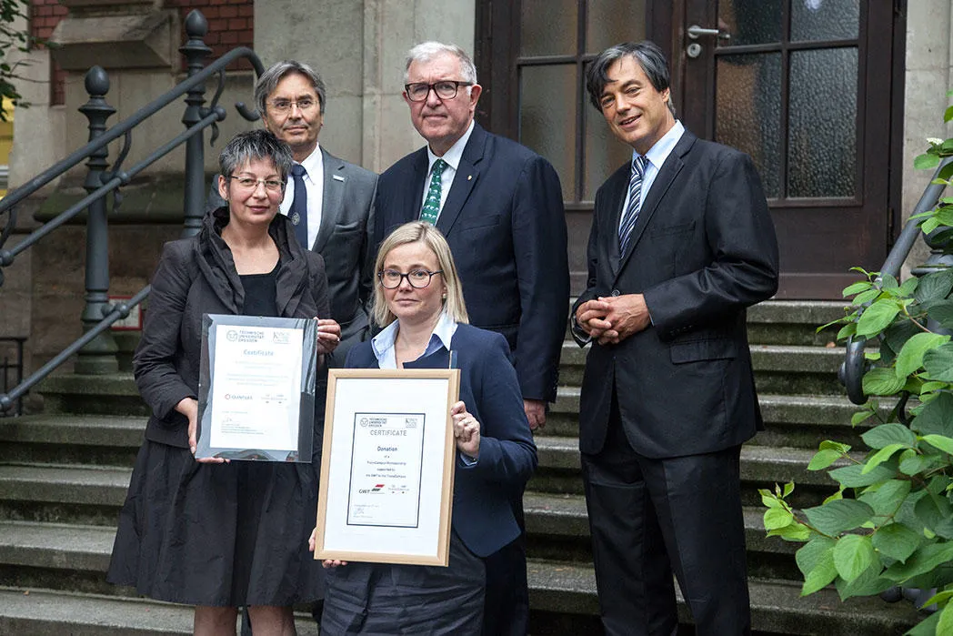 The Leadership Team of the new transcampus initiative in 2015 holding framed copies of the signed documents.
