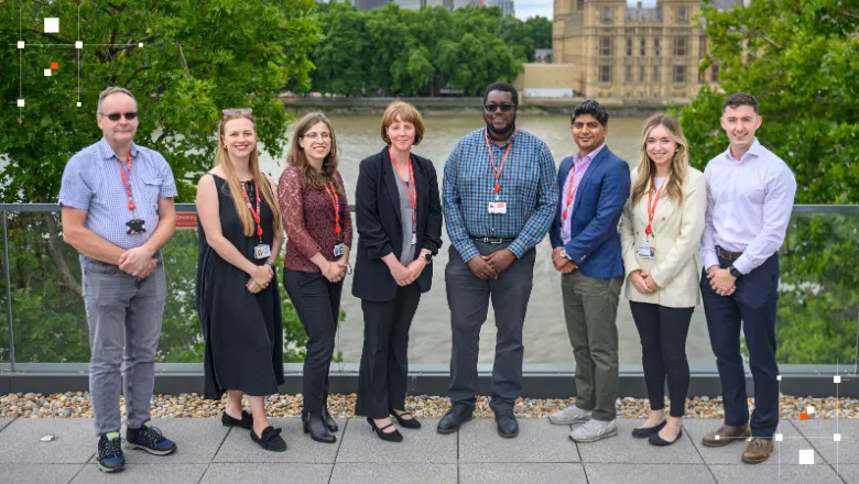 A team of seven people standing on a terrace overlooking the river Thames