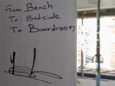 The words "From Bench to Bedside to Boardroom" scrawled on a wall and signed by Professor Sebastien Ourselin.