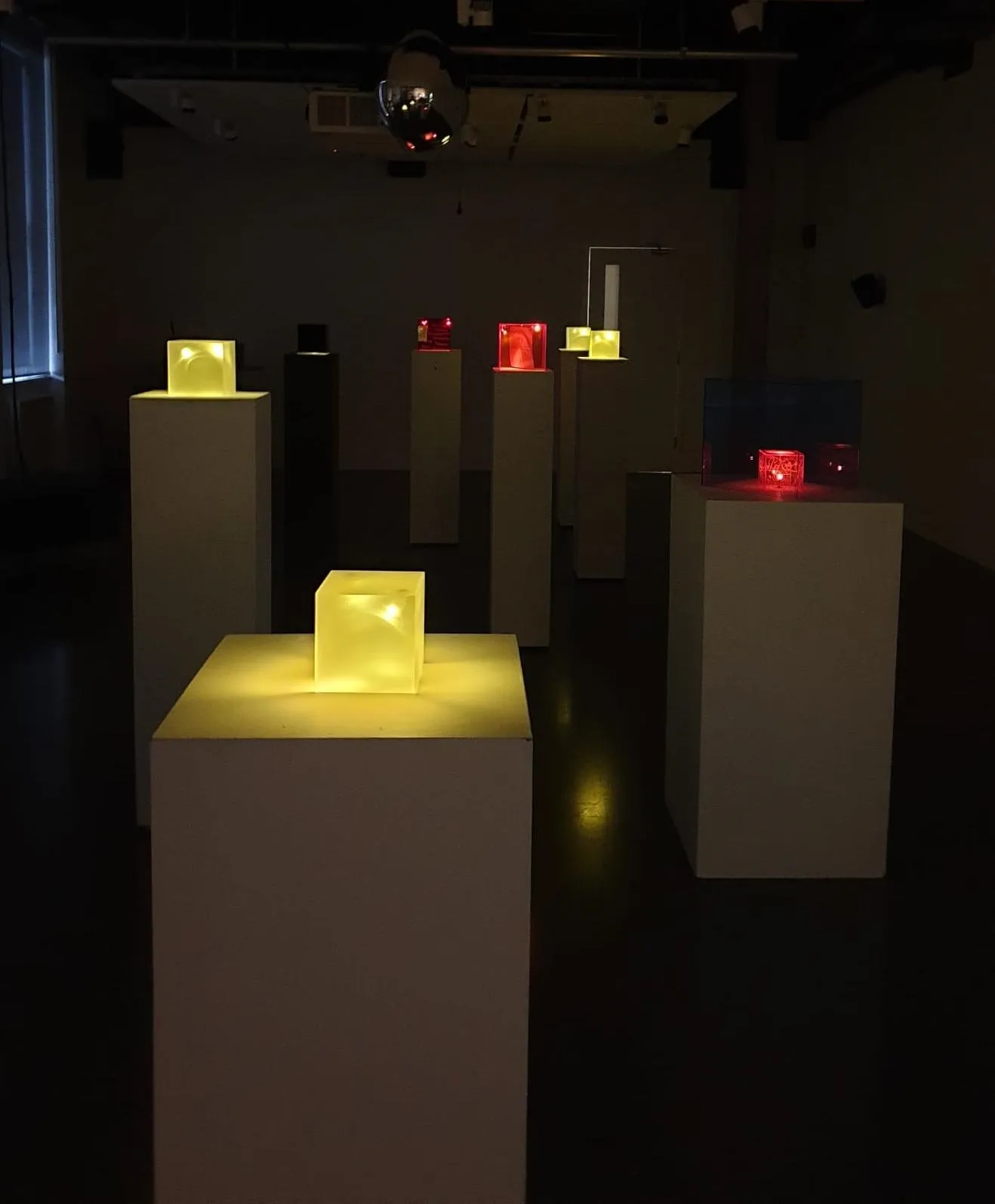 square boxes lit up on plinths in a dark room