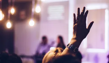 Someone raising their hand to ask a question at a seminar
