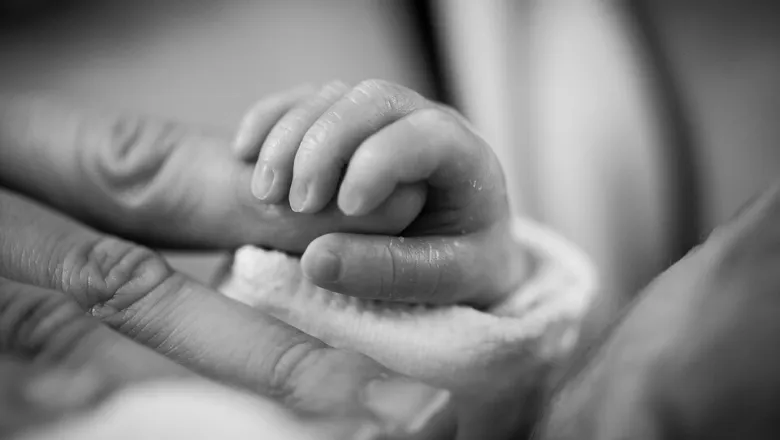 baby holding hand of mother