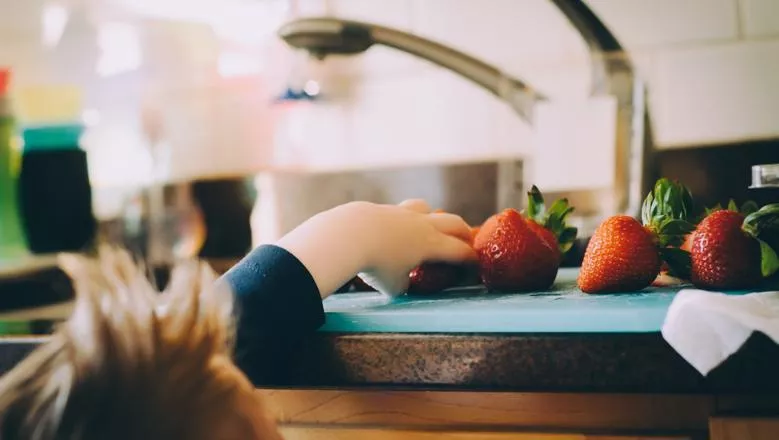 Child reaching for strawberries