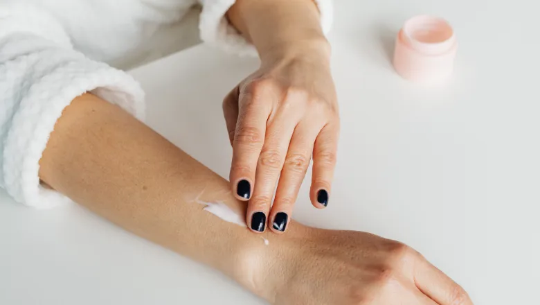 Someone applying body lotion to their arm