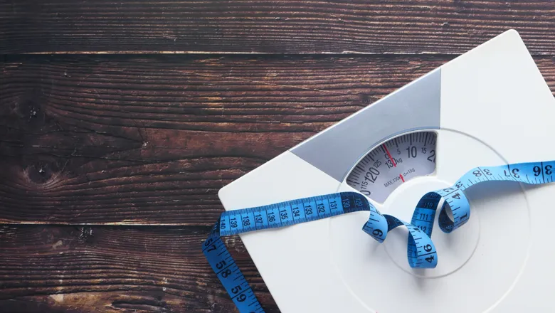 Weighing scales and tape measure on a wooden floor.