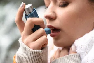 Age relatewd asthmatics - young woman using an inhaler