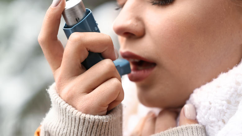 Person with asthma using an inhaler to aid breathing