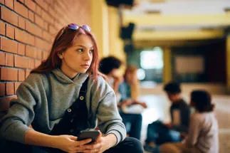 teen girl holding phone in school corridor