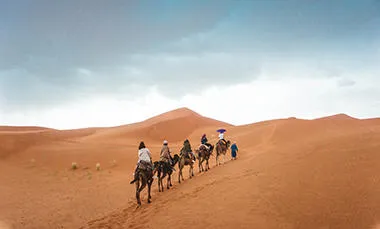 Riders on camels through the desert.