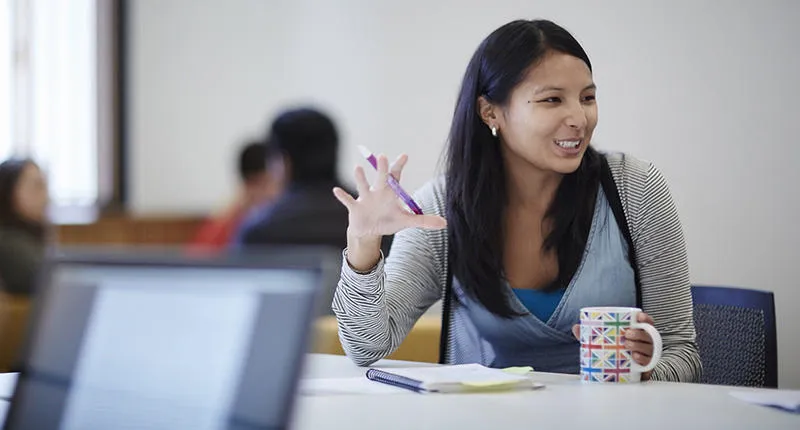 A student talking with cup and pen