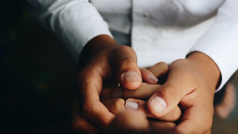 A pair of adult hands gently cradling a baby's hands