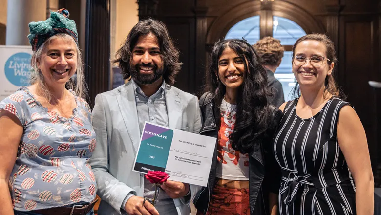 Four people smile at camera holding award certificate