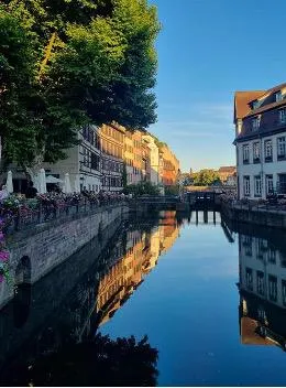 Canal in Petite France, Strasbourg, reflecting historic buildings and trees at golden hour