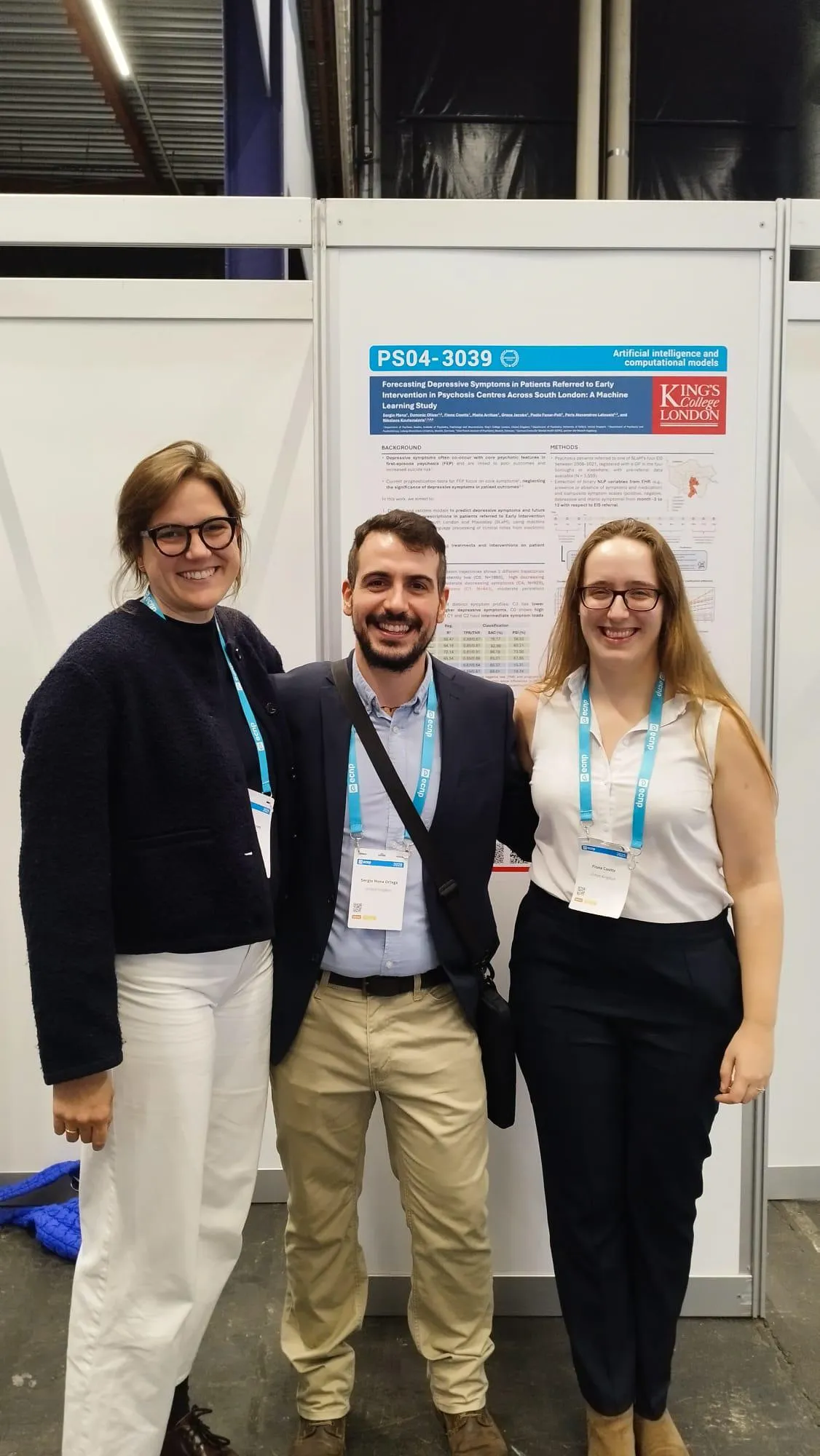 Three conference attendees smiling in front of a research poster display.