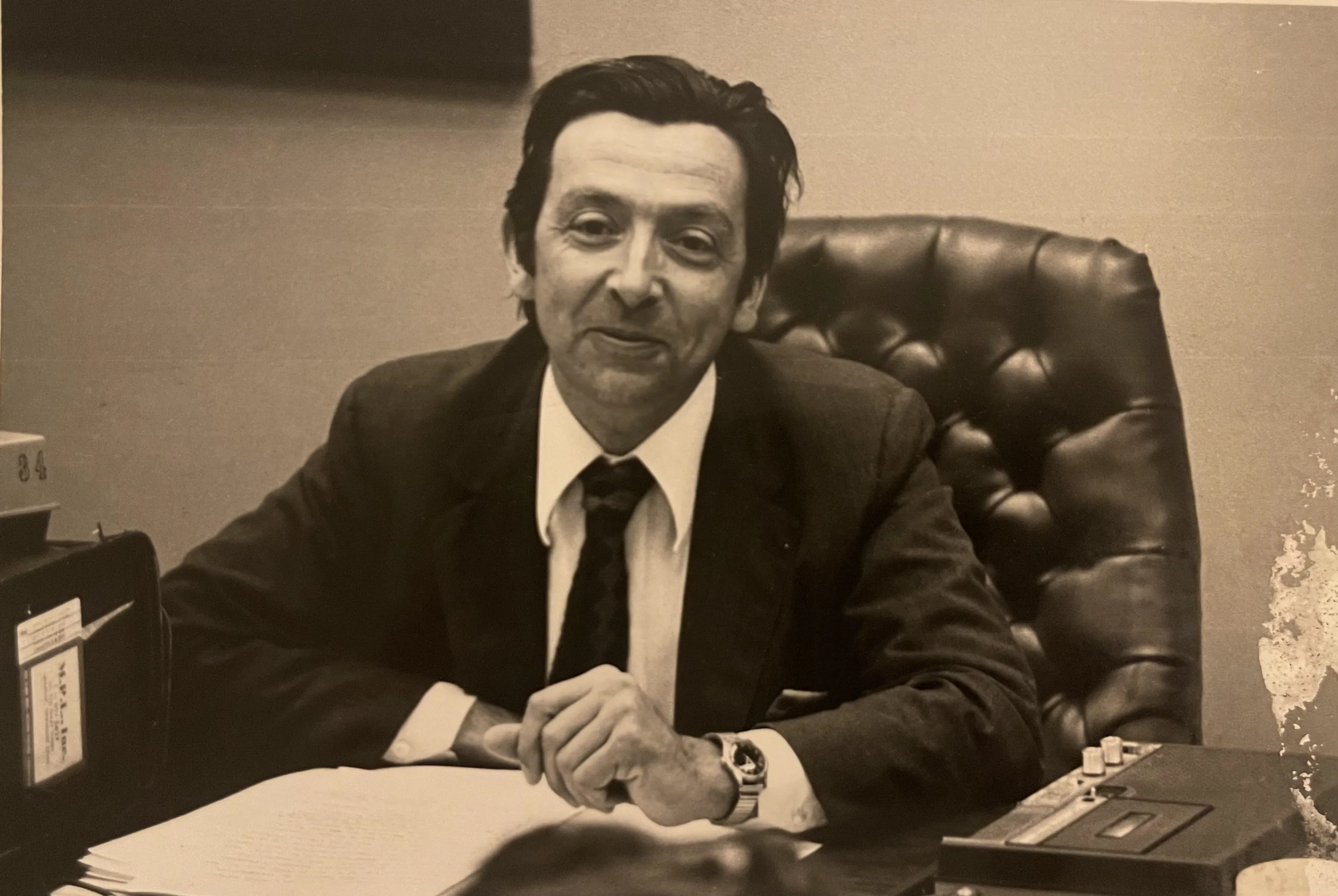Black and white photo of man seated at desk