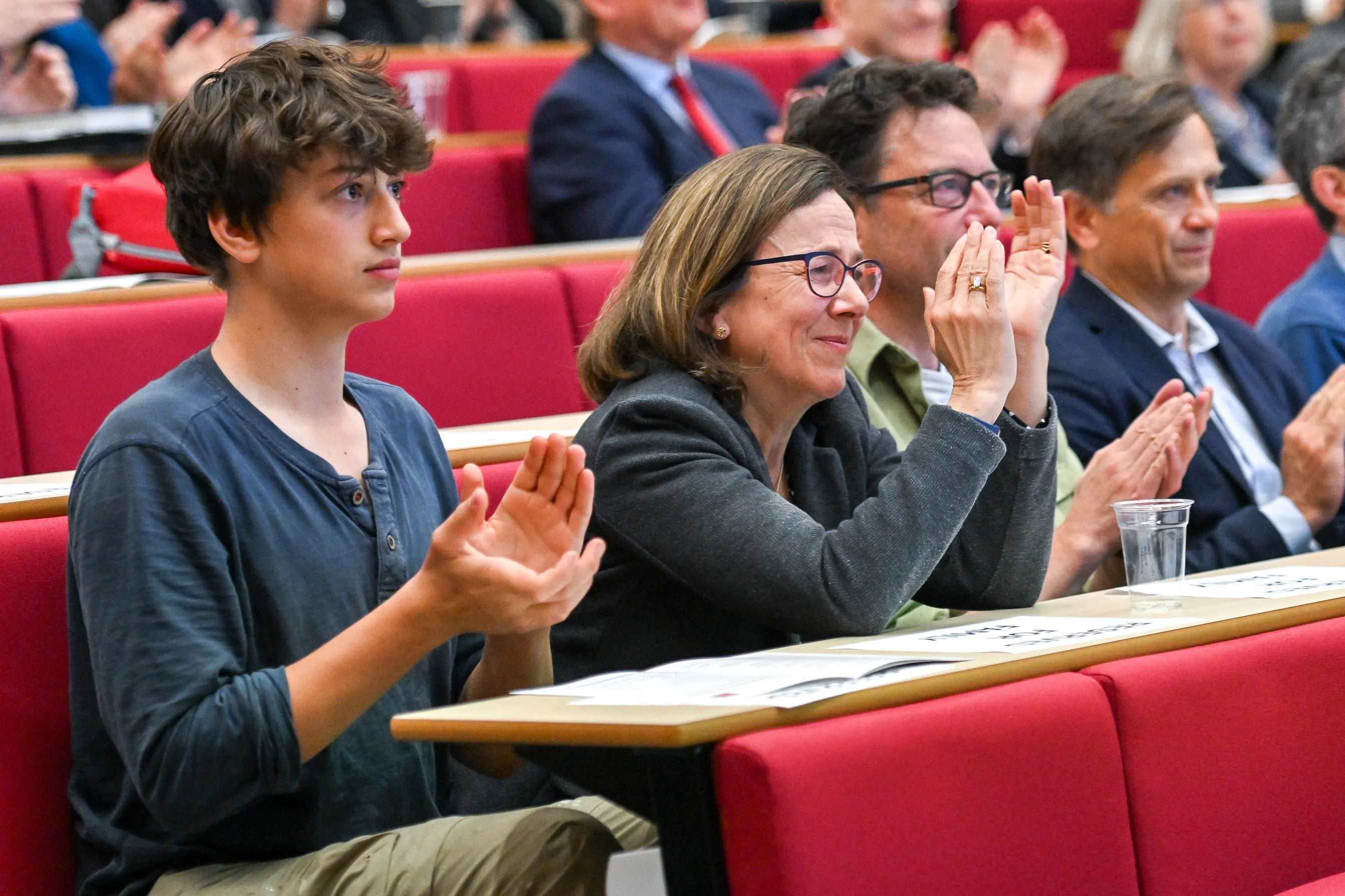 A row of people seated in a lecture theatre clapping