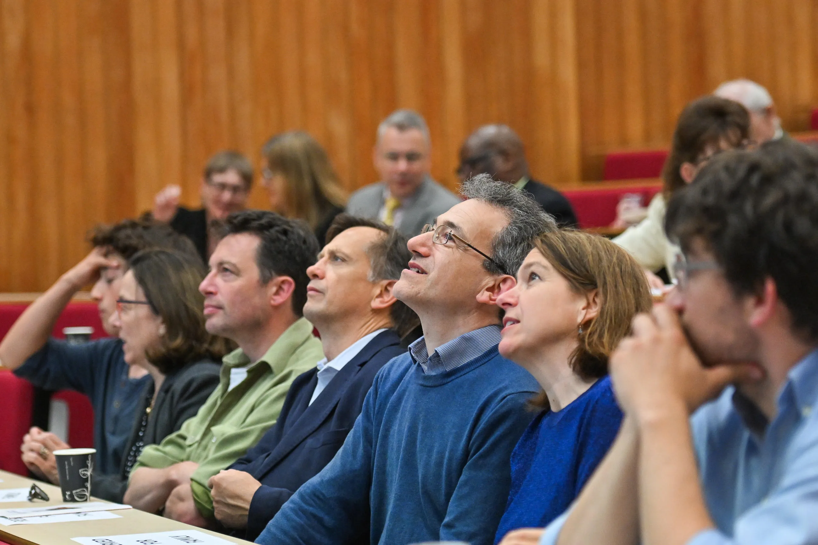 a row of people seated in a lecture theatre looking upwards towards the screen