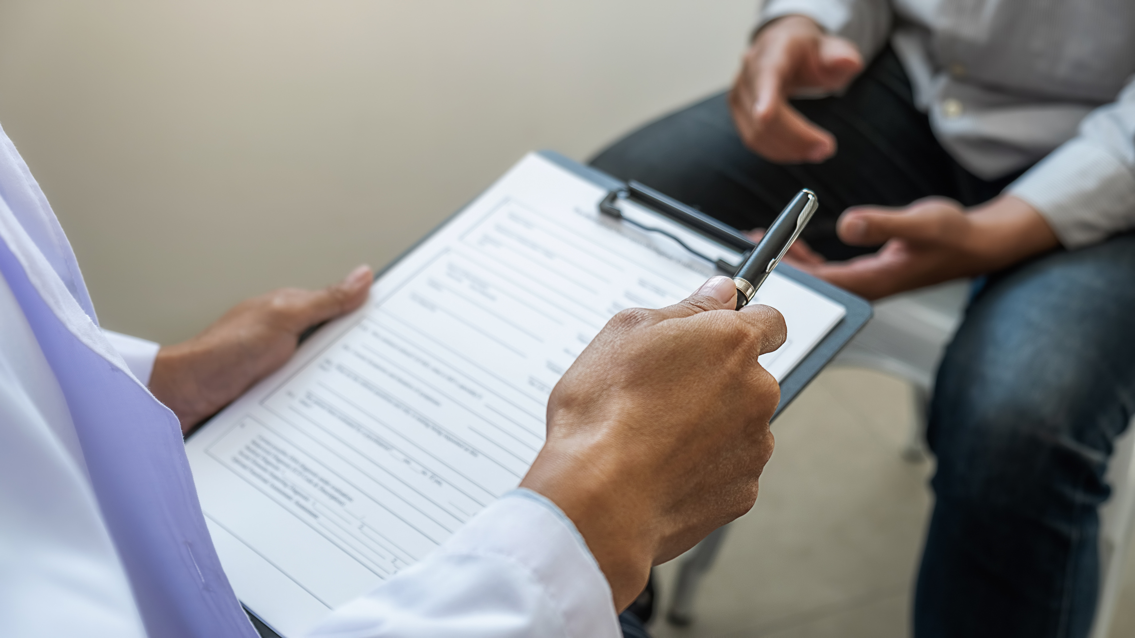 Clinician and patient completing a form on clipboard