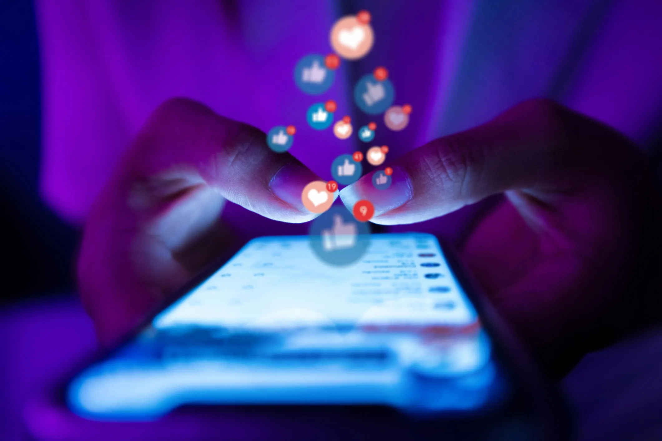 hands typing on smartphone with depiction of social media likes and engagements floating up