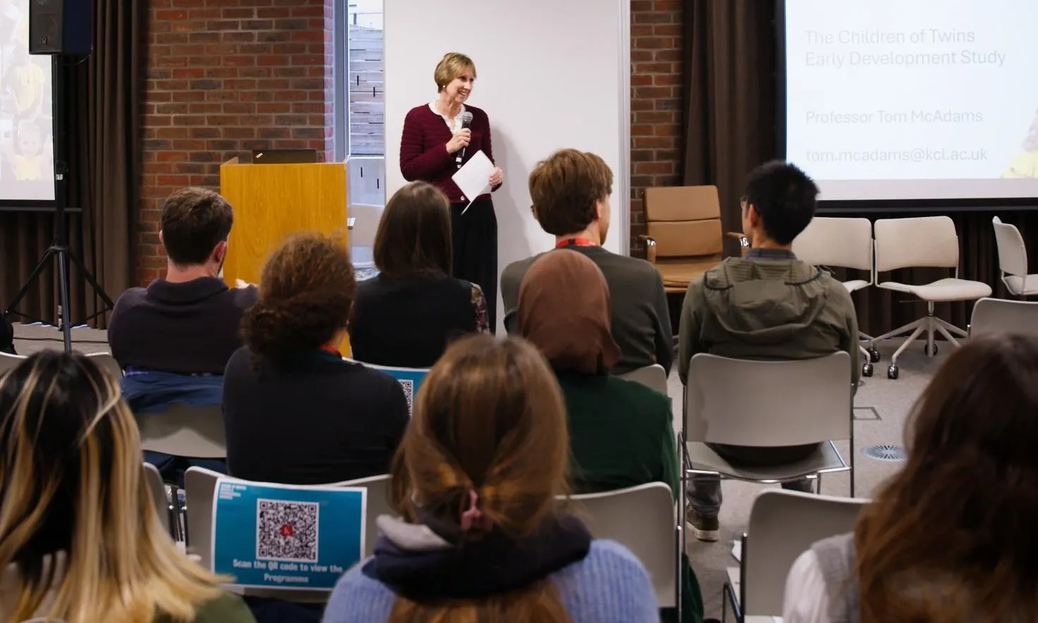 Woman presents at the front of busy conference room