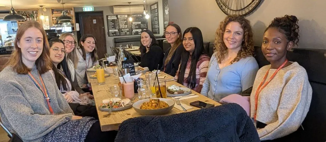 group of women seated at a table in a restaurant smiling at the camera