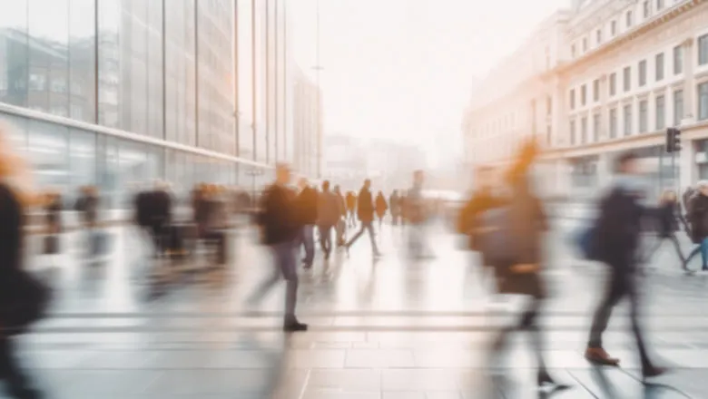 Blurred image depicting a crowd of people walking through a bustling city street