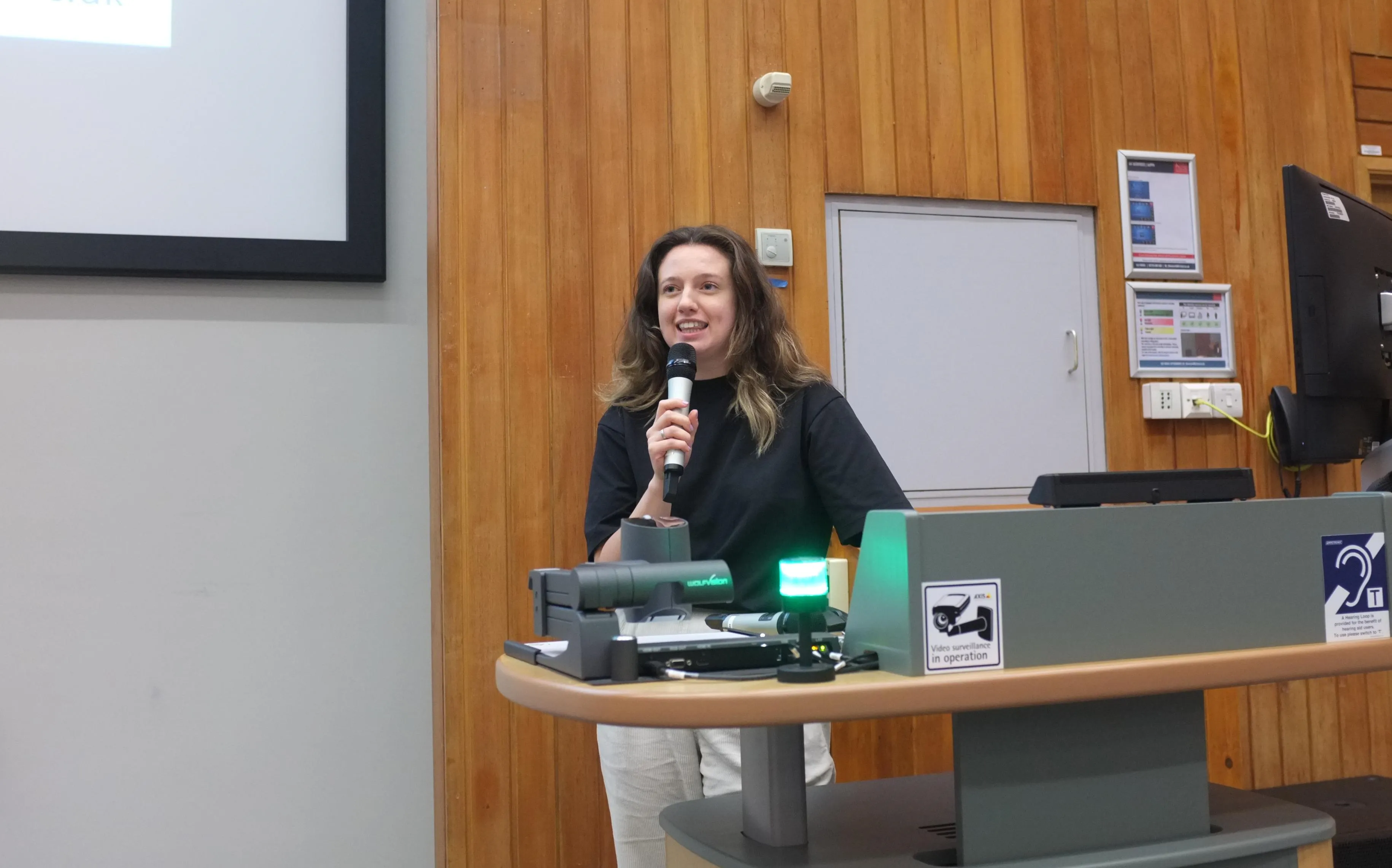 PhD student giving an oral presentation at the School of Neuroscience PhD Symposium filling up the room where posters are being presented