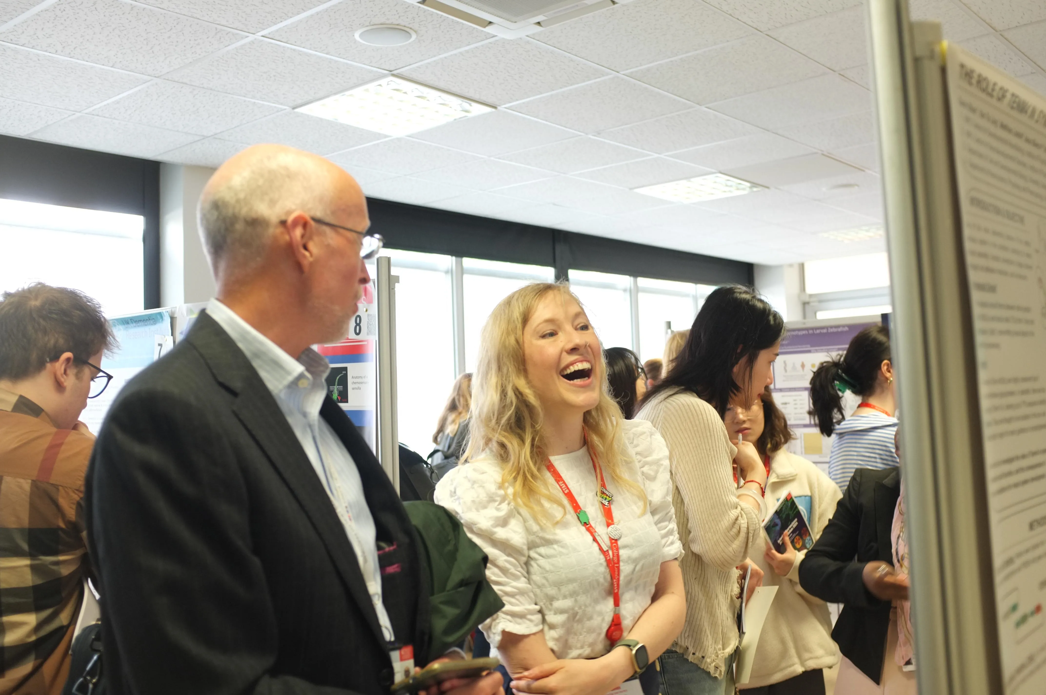 An attendee having a cheerful conversation with a senior academic at the school symposium