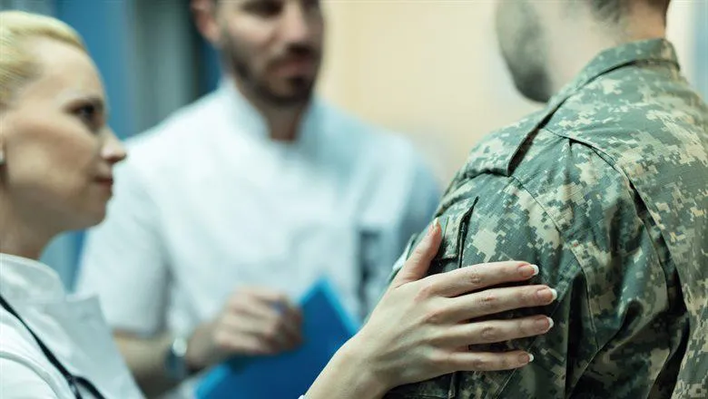 Man in military uniform speaking to two doctors