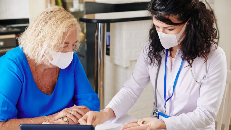 Woman sat with a doctor, both wearing face masks