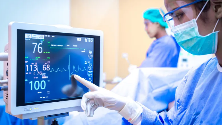 ICU worker in PPE looking at a monitor