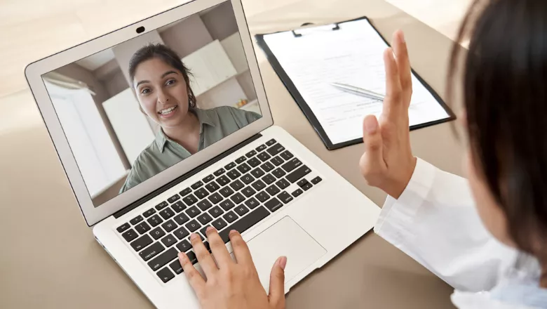 Image of a woman on a laptop screen, and a doctor waving at her