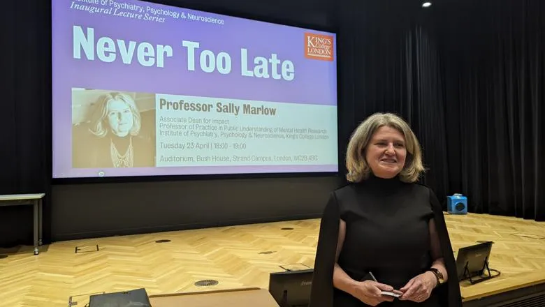 Professor Sally Marlow in front of a screen with the title of her talk Never Too Late 