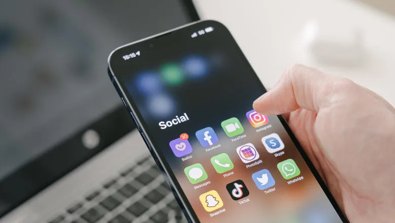 close up hand holding mobile phone displaying an array of social media apps