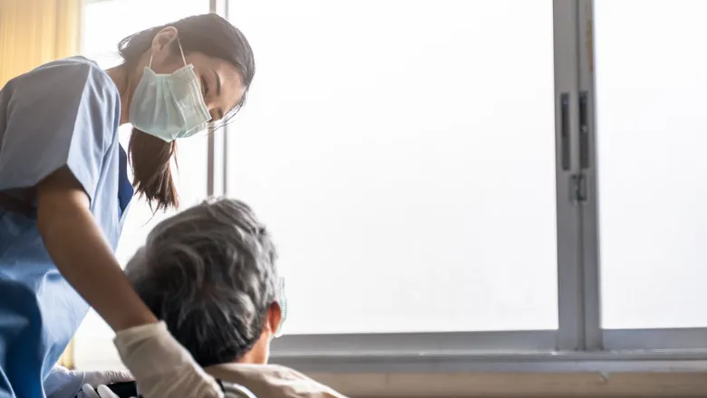 Nurse with a mask on smiling down at a patient