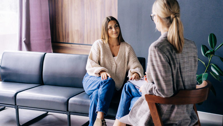 woman seated on sofa speaking to female therapist