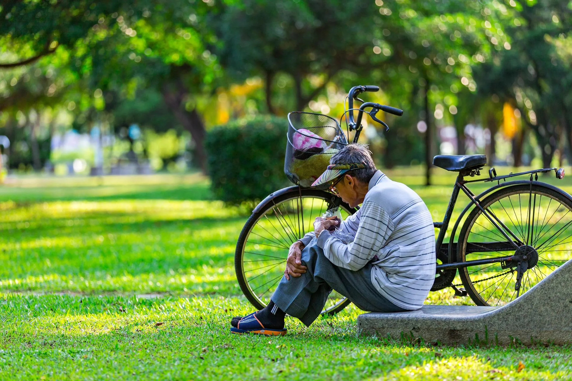Older man sitting on the floor next to a bicycle