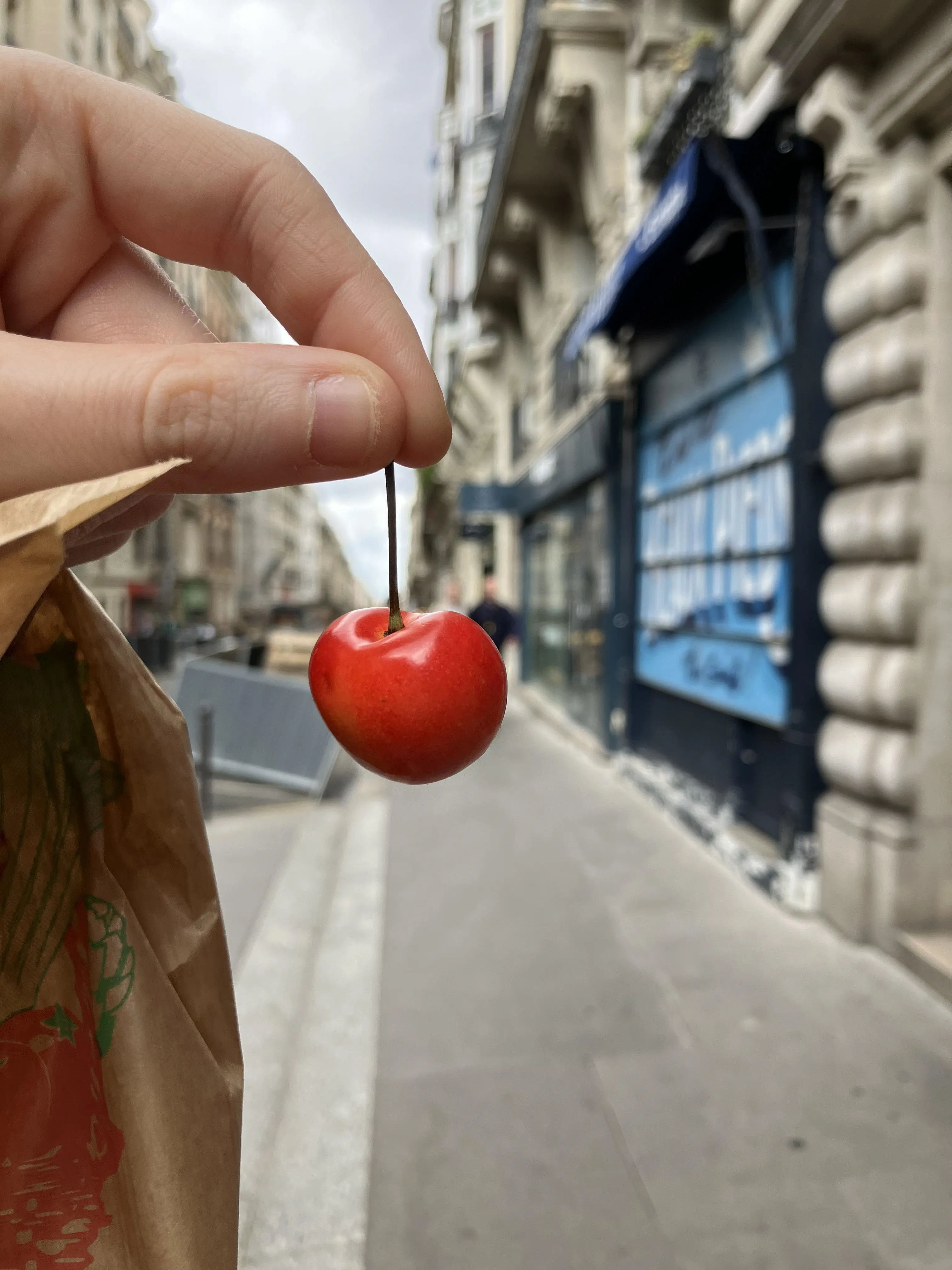 Person Holding a Cherry on the Street