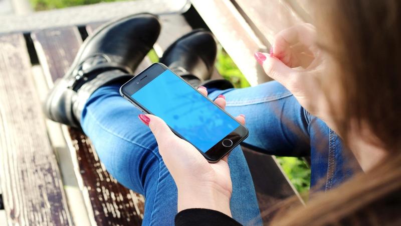 A person is sitting on the bench using an iphone