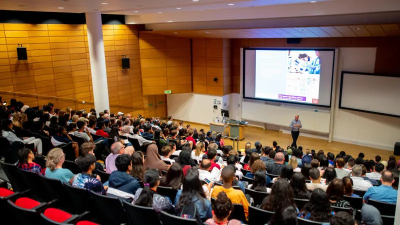 lecture theatre full of students watching a presentation on the screen