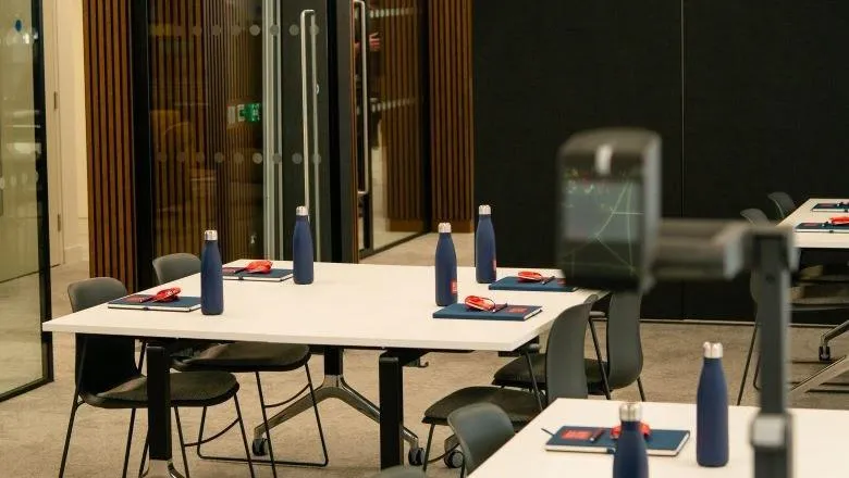 Image of professional education teaching space showing desks, chairs, projector and King's branded stationery.