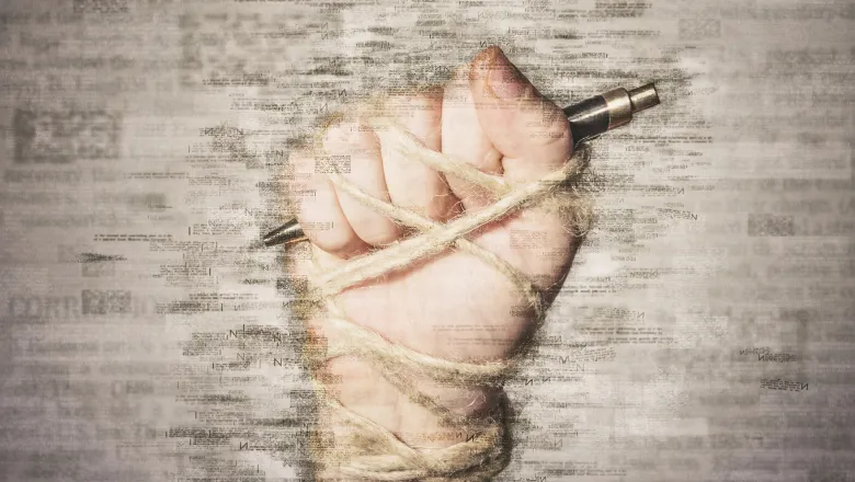 A hand holding a pen, bound. 