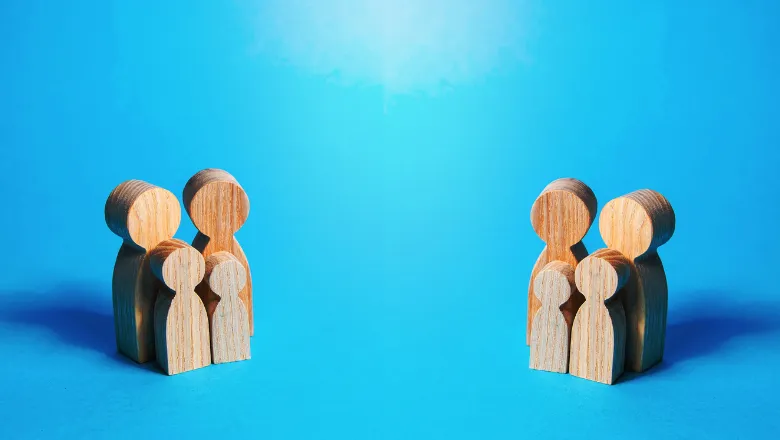 The image shows a family unit depicted by wooden carvings on a blue background.